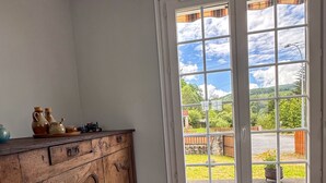 A kitchen with a wooden cabinet and a large window with a view of a garden and hills.