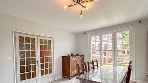 A spacious dining area with a large table and chairs, a wooden cabinet, and a ceiling light fixture.