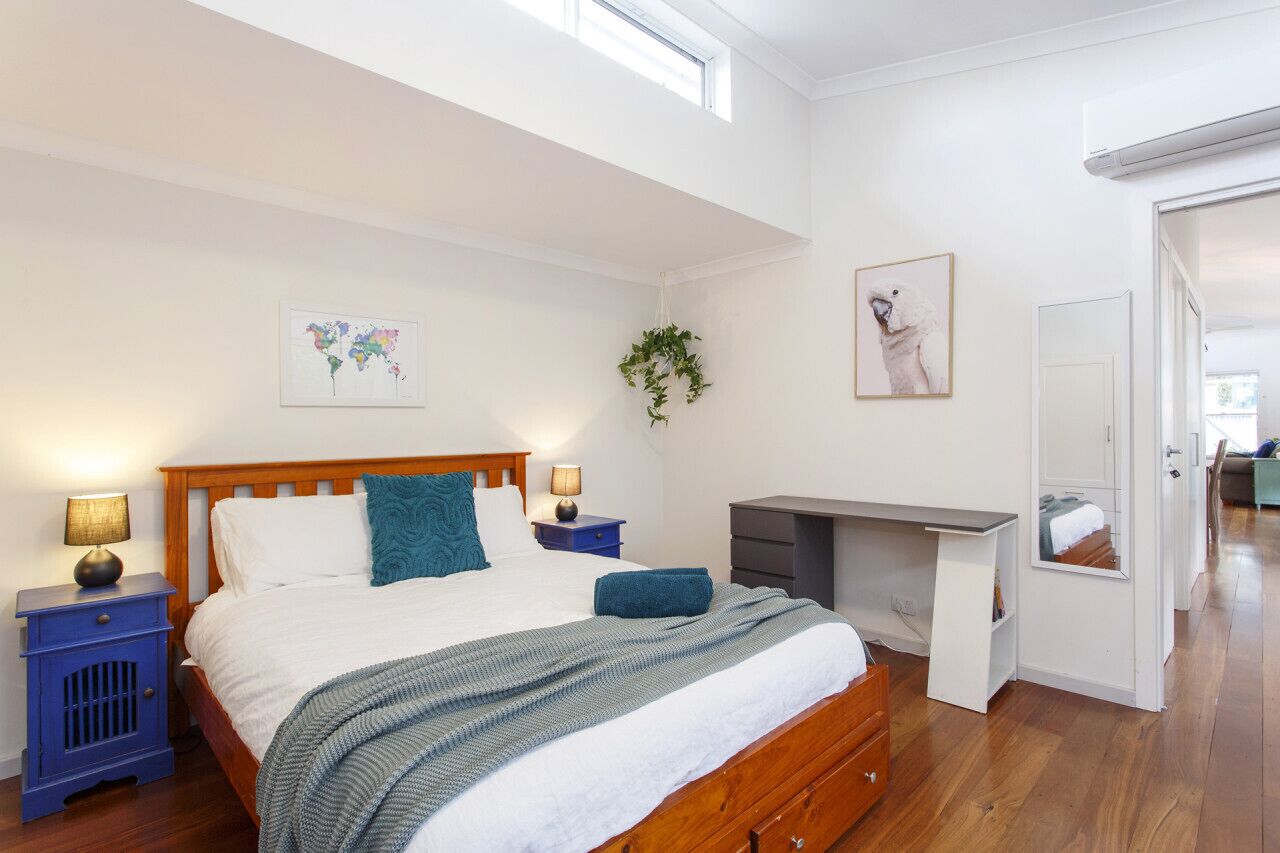 A bedroom with a wooden bed, a desk, a map artwork, and a plant.