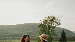 Two people on a wooden deck overlooking a lake with hills in the background. - Island View Cottage: Waterfront-BBQ-Sauna-AC-Wifi, Island View Cottage (Flatlands)