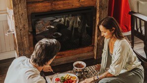 A cozy room with a fireplace, a dining table with plates of food, and a comfortable seating area. - Island View Cottage: Waterfront-BBQ-Sauna-AC-Wifi, Island View Cottage (Flatlands)