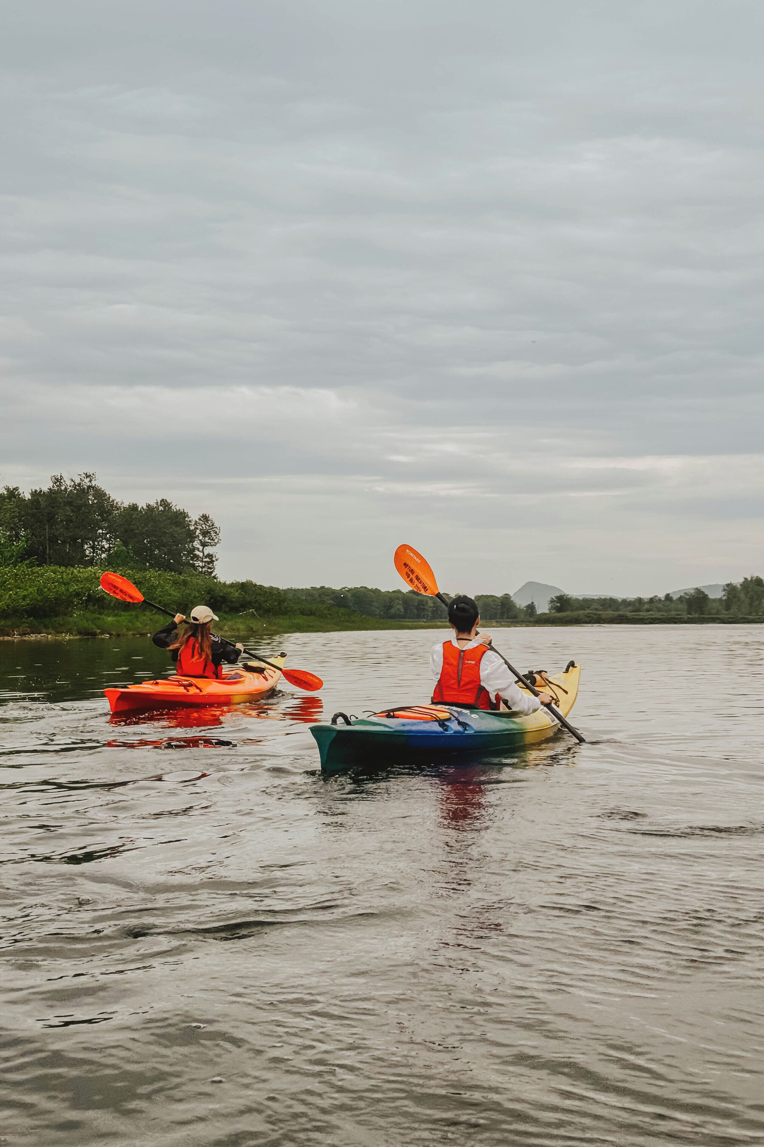 Deux kayaks sur une étendue d’eau calme, avec une rive boisée en arrière-plan.