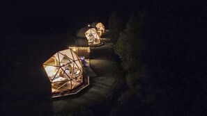 A series of illuminated geodesic dome structures, likely accommodations, connected by a pathway.