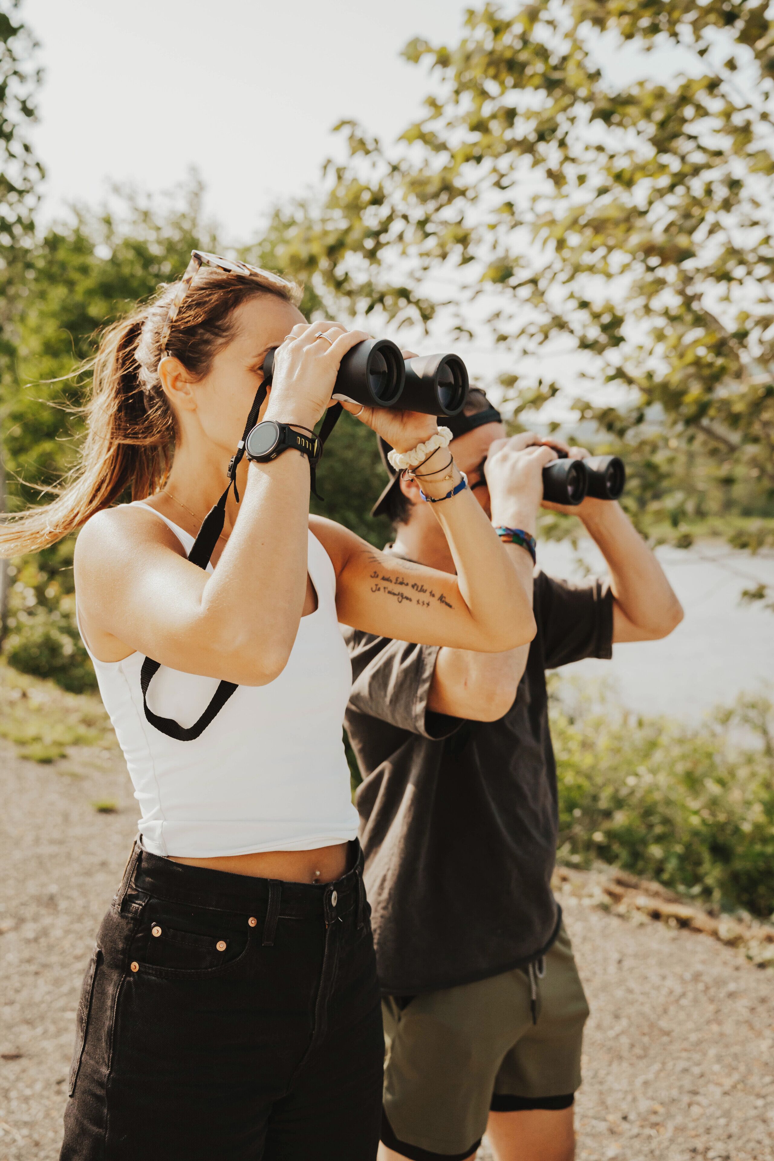 Two people using binoculars outdoors.