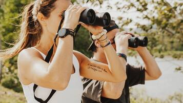 Two people using binoculars outdoors.