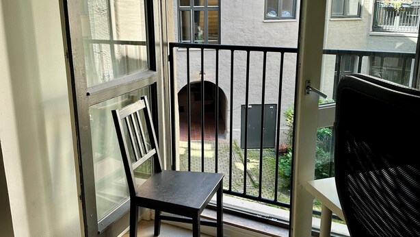 A balcony with a wooden chair, a view of a building with multiple windows, and a door leading to the outside. - Classical 3 bedroom, 2 bath, minutes walk from Royal Palace, Shopping & Downtown (Oslo)