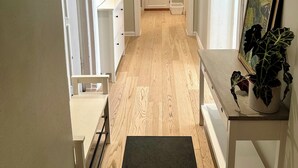 A hallway with a wooden floor, white walls, and doors leading to other rooms. There is a small table with a plant on it and a picture frame on the wall. - Classical 3 bedroom, 2 bath, minutes walk from Royal Palace, Shopping & Downtown (Oslo)