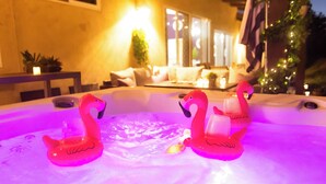 Una bañera de hidromasaje con dos flotadores con forma de flamenco rosa y un árbol de Navidad al fondo.