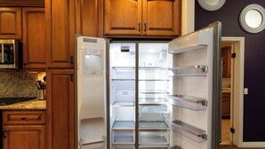 Una cocina con armarios de madera, encimera de granito y refrigerador empotrado.