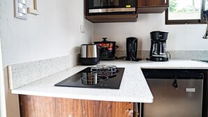 A compact kitchen with a built-in microwave, a coffee maker, and a stove. - Villas Dìwö (Cahuita)