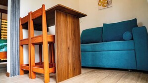 A wooden table with a shelf, a blue sofa, and a wall art piece. - Villas Dìwö (Cahuita)