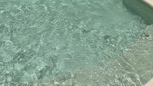 Ein helles Hallenbad mit Wasserspiel in der Mitte und Stufen zum Wasser.
