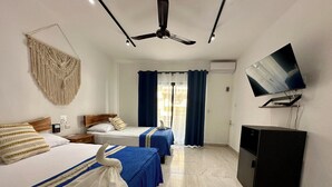 Ein Hotelzimmer mit zwei Betten, einem Deckenventilator, einem Fernseher und einer Minibar.