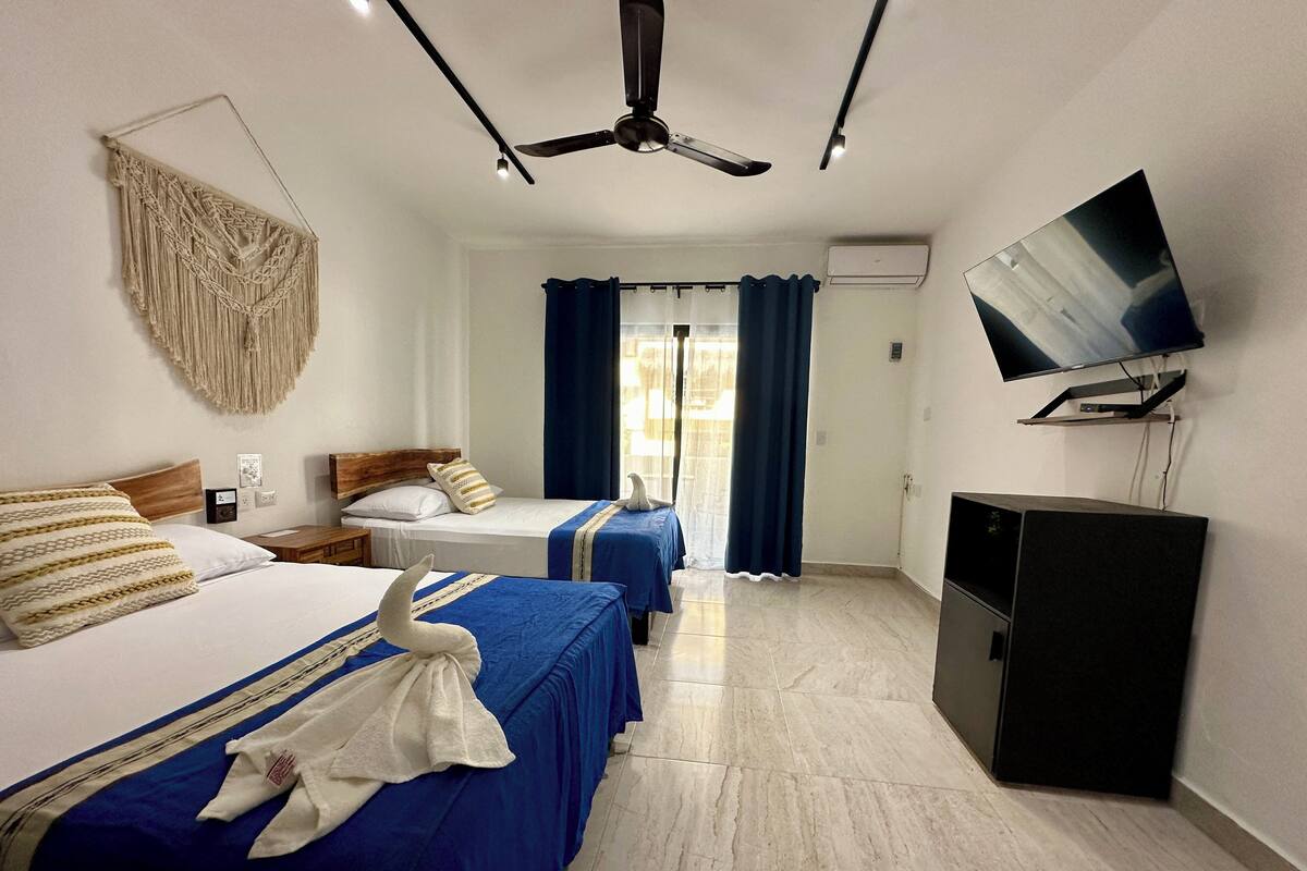 Une chambre d’hôtel avec deux lits, un ventilateur de plafond, une télévision et un mini-bar.