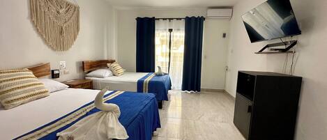 Une chambre d’hôtel avec deux lits, un ventilateur de plafond, une télévision et un mini-bar.