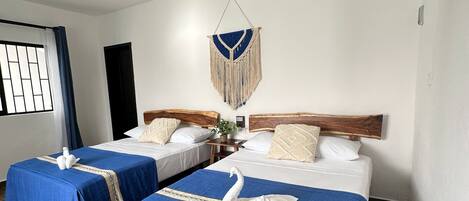 A hotel room with two beds, a ceiling fan, a wall-mounted air conditioner, and a window with curtains.