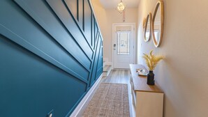 Un couloir avec un mur bleu, une porte blanche et une petite table sur laquelle se trouve un vase.
