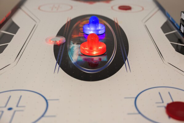 A close-up of a table hockey game with a puck and two illuminated pads.