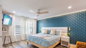 Une chambre à coucher avec un lit, une table de chevet et un téléviseur fixé au mur.