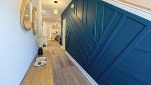 Un couloir doté d’un plancher en bois, d’un mur d’accent bleu et d’une porte au fond.