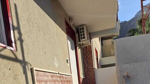 A set of concrete stairs leading up to a building entrance with a red door and a window. - Guests' Nest (Castellammare del Golfo)