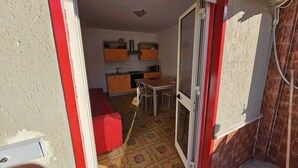 A compact kitchen with a dining area, a red bench, and a patterned floor. - Guests' Nest (Castellammare del Golfo)