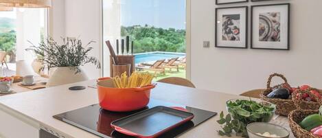A modern kitchen with a view of a pool, a tablet on the counter, and various kitchen items.
