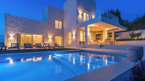 A modern house with a swimming pool, outdoor seating, and a stone facade. - Villa Selena Antequera by Ruralidays (Málaga)