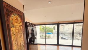 Ein geräumiges Zimmer mit großem Fenster, einem Kühlschrank und einem dekorativen Gemälde an der Wand.
