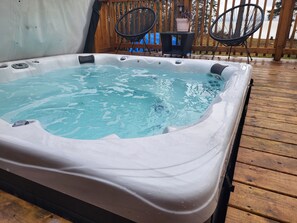 A hot tub on a wooden deck with a view of a lake. - 4 Season Lakefront Cottage with Hot Tub (Little Deer Lake)
