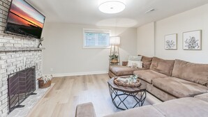 Un salon avec une cheminée, un grand téléviseur à écran plat, un canapé, une table basse et une lampe.