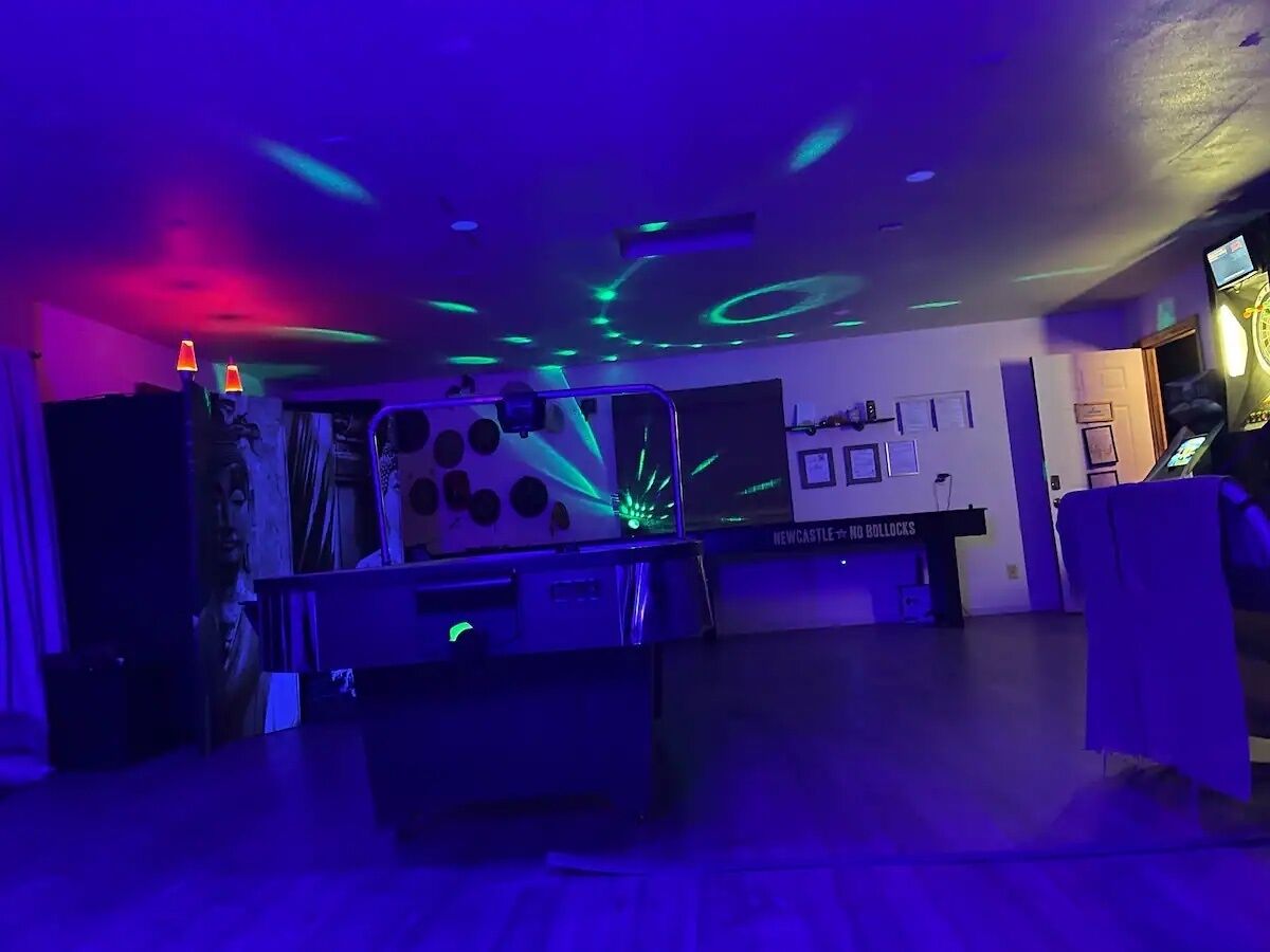 A room with a pool table, neon lights, and a sign reading "Newcastle No Bullocks."