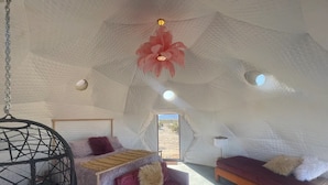 A cozy, tent-like room with a bed, a sofa, and a hanging chair.