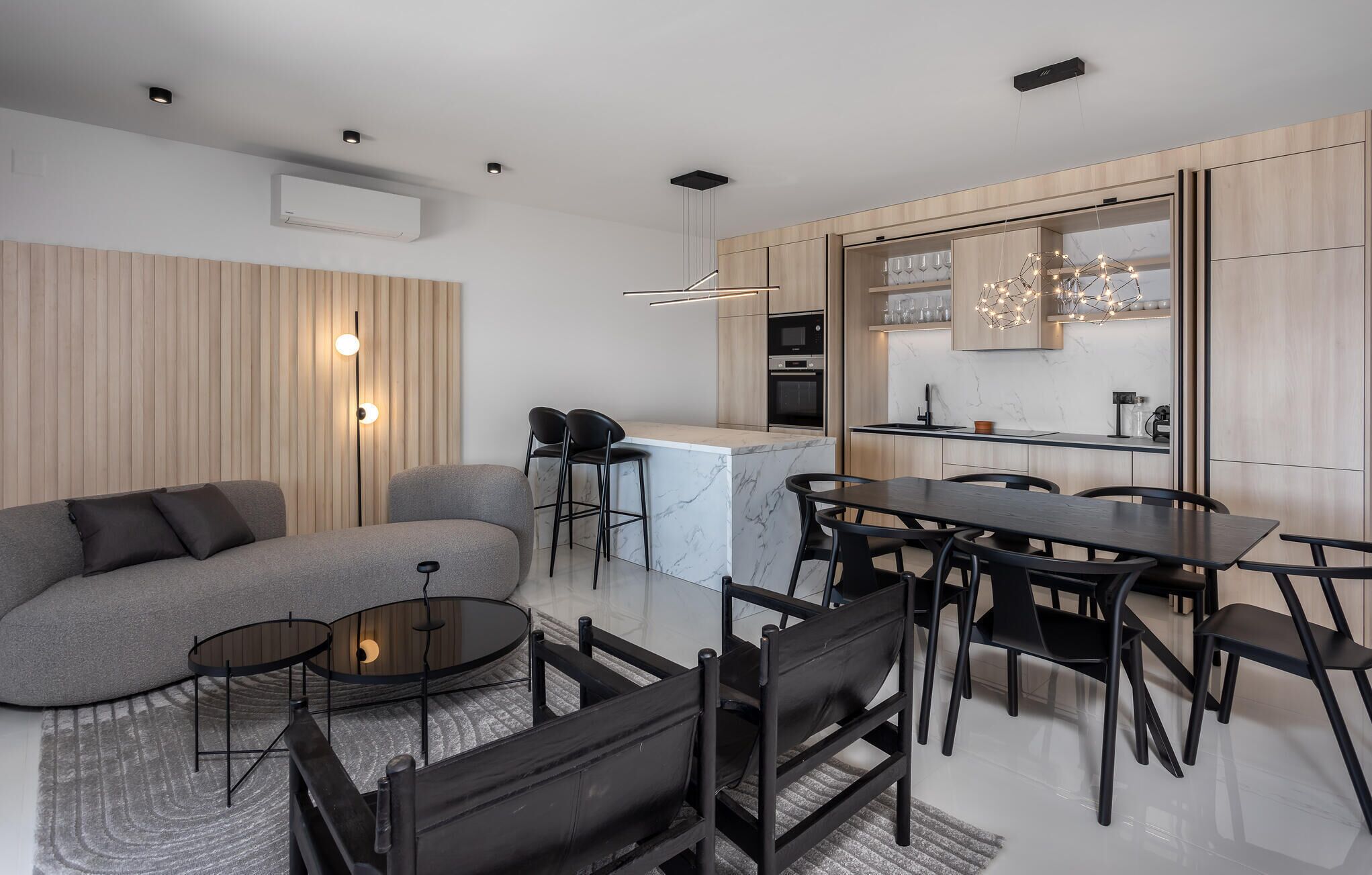 Une cuisine moderne dotée d’un îlot central, un coin repas avec une table et des chaises, et un espace de vie avec un canapé et une table basse.