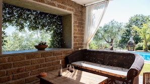 A cozy outdoor seating area with a wicker sofa, a wooden table, and a potted plant. - Olvietello With 3 Bedrooms and 3 Bathrooms (Trevignano Romano)