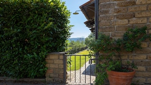 A brick wall with a metal gate leading to a paved area. - Olvietello With 3 Bedrooms and 3 Bathrooms (Trevignano Romano)