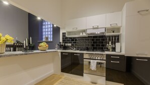 Una cocina moderna con armarios oscuros y claros, horno empotrado y ventana con vistas.