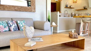 A modern living room with a wooden coffee table, a grey sofa with patterned cushions, a woven basket, and a magazine.