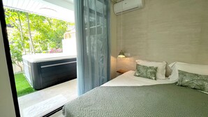Une chambre à coucher comprenant un lit, une table de chevet, une fenêtre avec des rideaux et un appareil de climatisation.