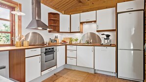 A modern kitchen with white cabinets, a stainless steel range hood, and a built-in dishwasher. - 3 bedroom beautiful home in Melby (Melby)