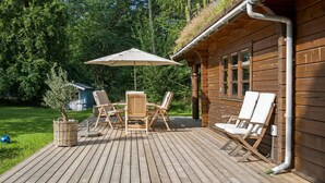 A wooden deck with outdoor furniture, including a table and chairs, and a large umbrella. - 3 bedroom beautiful home in Melby (Melby)