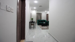 A hallway with a wooden door, a small table with a plant, a green sofa, and a coffee table. - STAR NIGHT FURNISHED APARTMENTS (Fahaheel)
