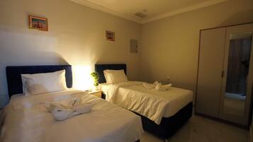 Habitación de hotel con dos camas, un armario y una pequeña mesa con una planta.
