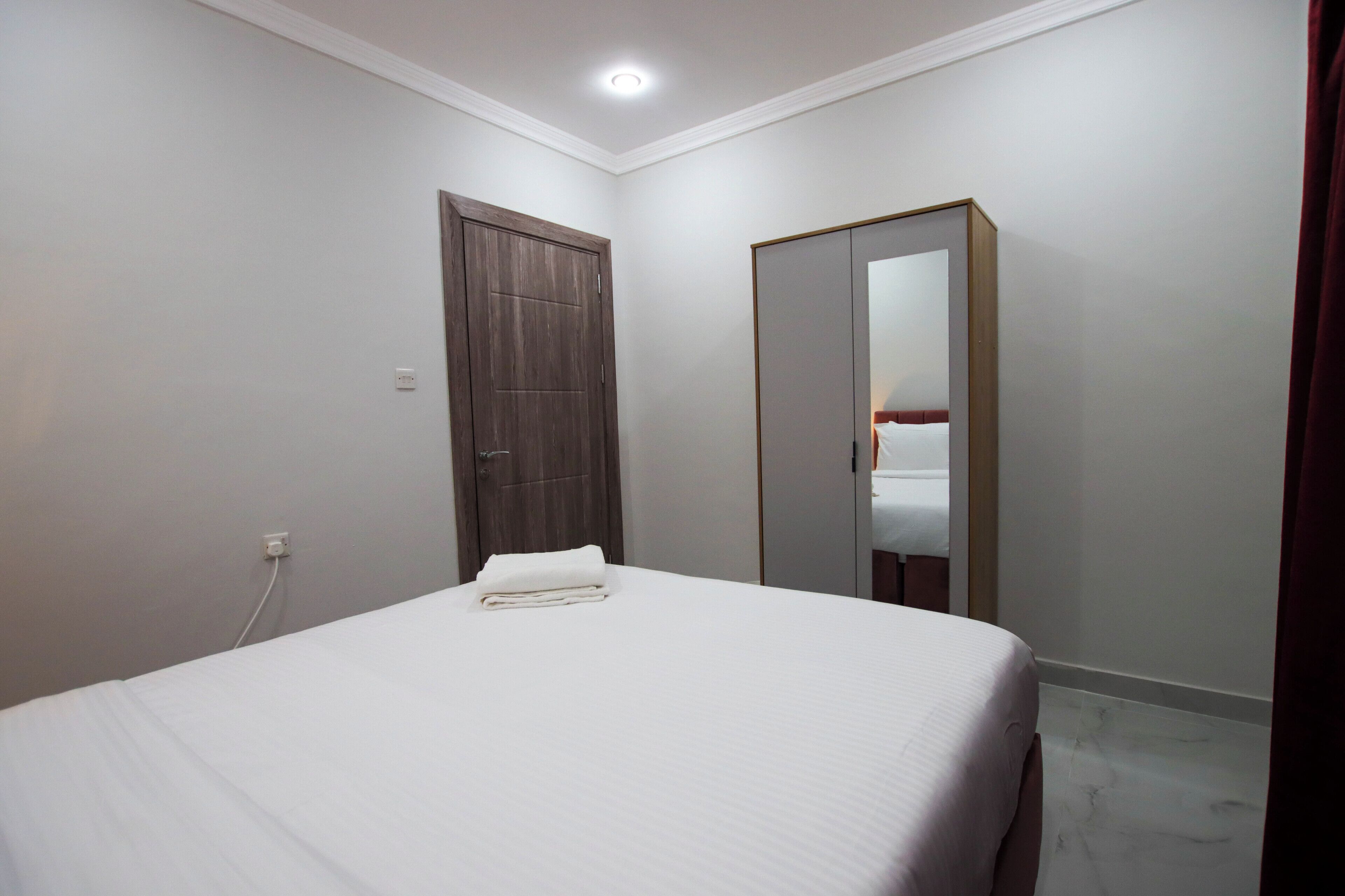 A bedroom with a bed, a wardrobe, and a mirror.