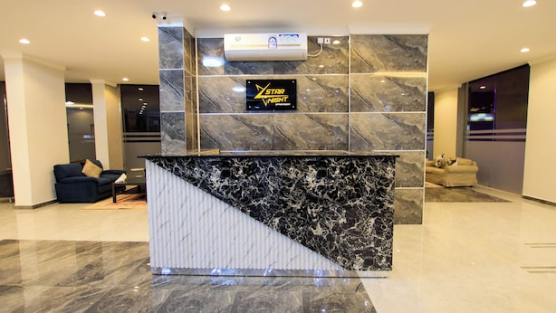 A reception desk with a marble finish, a sign reading "Star Night Apartment," and a modern interior design with a sofa and a chair in the background. - STAR NIGHT FURNISHED APARTMENTS (Fahaheel)