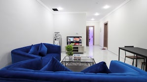 A modern living room with a blue sofa, a coffee table, and a flat-screen TV. - STAR NIGHT FURNISHED APARTMENTS (Fahaheel)