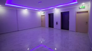 A spacious hallway with a polished marble floor, purple LED lighting, and doors leading to rooms. - STAR NIGHT FURNISHED APARTMENTS (Fahaheel)
