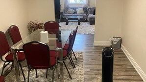 A dining area with a table and chairs, a coffee table, a rug, and a standing heater. - Downtown Apartment 6 or 7 People (Bowmanville)