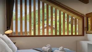 Ein Hotelzimmer mit einem Bett, einem Fenster mit Holzjalousien, einem Schreibtisch und einer Lampe.