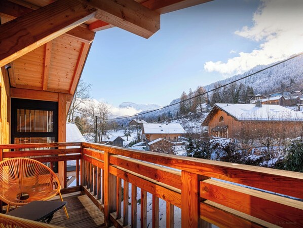 A wooden cabin with a balcony overlooking a snowy village. - MontCriou - ski-in, ski-out apartment for 10 near Samoëns - OVO Network (Samoëns)